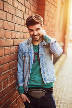 bir tuğla duvara poz ve kamera, osteopenik resim ile modern bir öğrenci için gülümseyen yakışıklı ve güzel genç adam