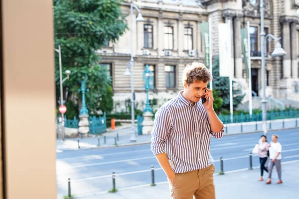 Mladý muž chůze a mluvení na mobil — Stock fotografie