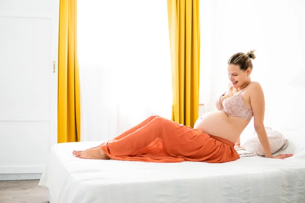 Mujer embarazada sentada en su cama — Foto de Stock