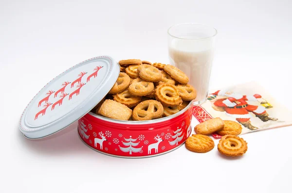 Glass of milk and metal box with Christmas cookies
