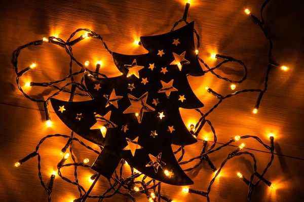 黒い金属木製の背景上にクリスマス ツリーの後ろに小さな黄色のクリスマス ライト — ストック写真