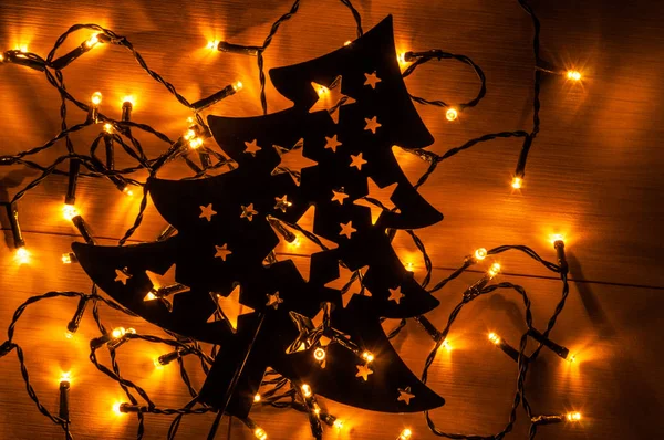 黒い金属木製の背景上にクリスマス ツリーの後ろに小さな黄色のクリスマス ライト — ストック写真
