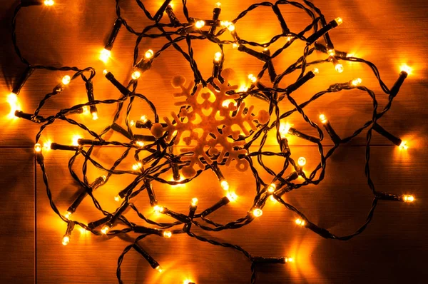 クリスマスの照明と木製の背景に人工雪の結晶 — ストック写真