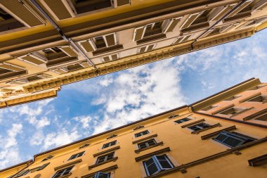 İki sarı bina ve aralarında mavi bulutlu gökyüzü