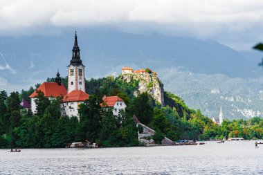 Gölün ortasında, renkli ağaçlarla çevrili eski bir kilise.