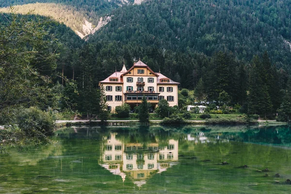 Forest house on the lake, reflecting in blue water