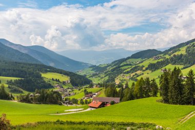 Arka planda küçük kırsal evleri ve ormanı olan huzurlu Alp Vadisi