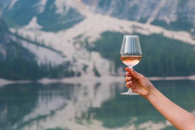 Braies Gölü 'nün arka planında bir bardak şarabı olan kadın eli.