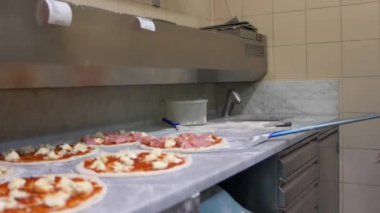 Şef pizza spatula ile hazır pizza daire tablosundan alır, eliyle düzeltiyor ve üzerinde yalan diğer pizza circles tablo yükseltir.