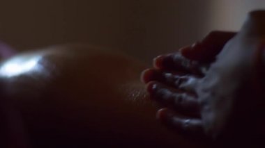 Alt bacak ve dairesel hareketlerle deri içine yağ ovmak eller masör, yakın çekim. Masöz masaj yapar. Işıkta penceresinden.