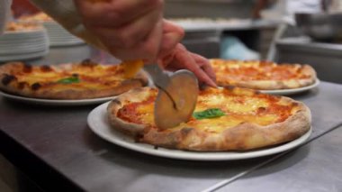 Mutfakta pizza bıçağı ile metal bir tabloda bir adam ile ikinci el beyaz tabak kenarına tutan 4 parçalar halinde keser. Yakın çekim.