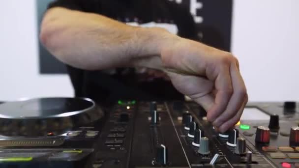 DJ kéz érintése gombok és a csúszka a fedélzeten a közeli hangkeverő vezérlő. Keverjük össze a számokat, elektronikus és pop zenét játszik a professzionális hang berendezésre, a klub.