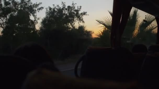 道路と夕方にはバスの窓からの眺め 明るいオレンジ色の夕日 女の子に内側からバスの窓から見える — ストック動画
