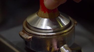 Metalik temperanın yakın çekim. Taze kahve tamping ile öğütülmüş kahve hazırlama. Baştan sona kahve yapıyorum. Taze çekilmiş kahveyi kurcalamak. Eller baristalar.