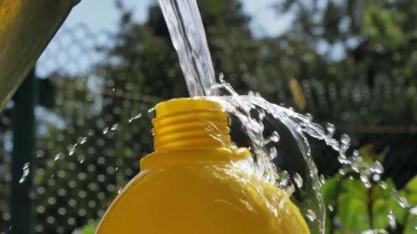Χύνοντας Νερό Από Έναν Μεταλλικό Κουβά Ένα Φωτεινό Κίτρινο Μπουκάλι — Αρχείο Βίντεο