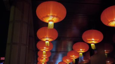Çin, Makao - Mayıs 2019. Kırmızı, sokaklardan birinde tavandan sarkan sarı saçaklı yuvarlak fenerler. Sütunlar arasında çekim.