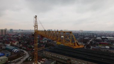 Novosibirsk, Rusya - 2 Ekim 2018:Bulutlu havalarda gün boyunca şehrin arka planına karşı yüksek sarı metal bir vinç havadan fotoğraf. Alt kattaki konut ve endüstriyel binalar.