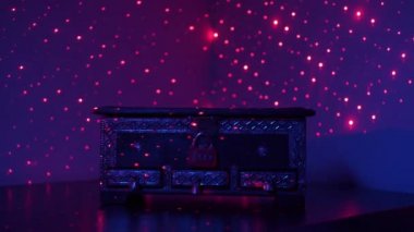 Bir göğüs, orta boy, desenler, kırmızı bir kombinasyon kilidi kapalı, renkli ışıklar ile dökülür karanlık bir odada, bir masa üzerinde duruyor. Bulmaca kavramı.