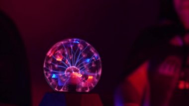 Karanlık bir odada şimşek çakan, kırmızı ışıkla aydınlatılan ve insanların parmaklarını soktuğu bir topun yakın çekim. Close. Bulmaca kavramı.