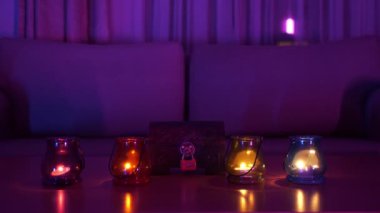 Bir bastırılmış pembe ışık ile bir oda, bir kanepe ve mumlar yanar renkli lambalar ile bir arada kilit ve renkli lambalar ile bir göğüs olduğu bir masa vardır. Bir mumun alevi lambalarda çalıyor..