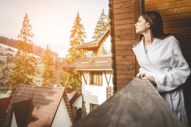 Kız bir dağlık alanda bir teraslı ev üzerinde duruyor. İyi kış şehrinde hava durumu.