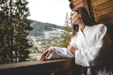 Kız bir dağlık alanda bir teraslı ev üzerinde duruyor. İyi kış şehrinde hava durumu.