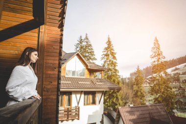 Kız bir dağlık alanda bir teraslı ev üzerinde duruyor. İyi kış şehrinde hava durumu.