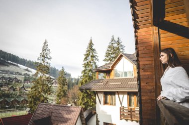 Kız bir dağlık alanda bir teraslı ev üzerinde duruyor. İyi kış şehrinde hava durumu.