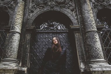 Genç kız eski Gotik duvar arka plan üzerinde duruyor.