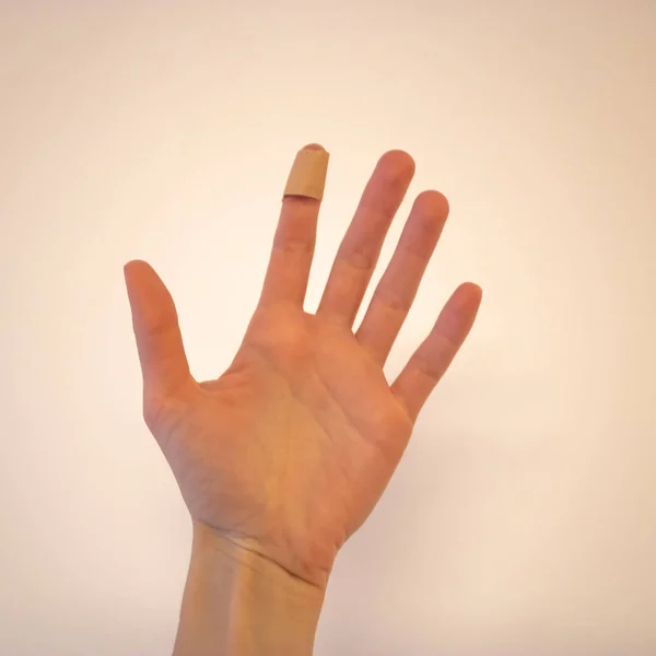 Рука жінки з групою допомоги на індексному пальці на білому — стокове фото
