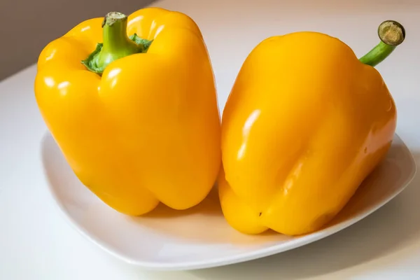 Two yellow bell peppers on the white porcelain dish closeup - Im — Stock Photo, Image