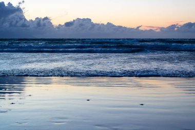 Yaklaşan dalgalar ile gün batımında plaj - Resim