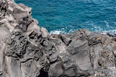 Volkanik kaya oluşumları backgr üzerinde mavi deniz ile doku