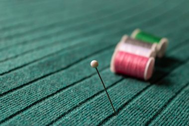 Yeşil tekstil arka planında renkli dikiş ipliklerine sahip beyaz iğne - Resim