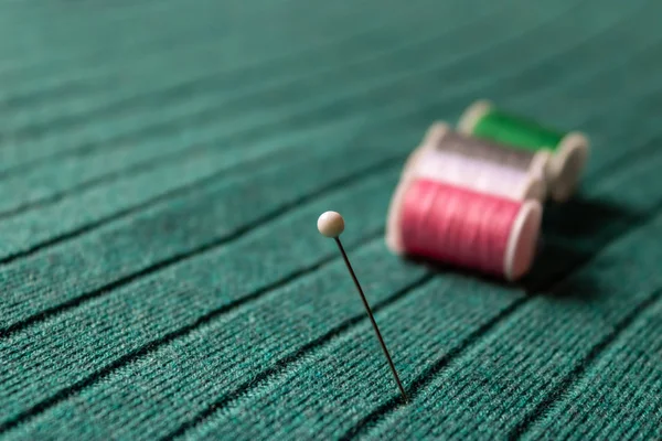 White pin with the colorful sewing threads on the green textile background - Image — 스톡 사진