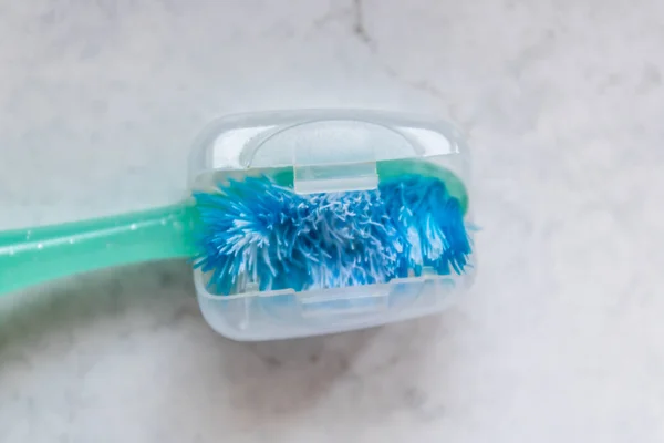 Used old toothbrush with a plastic sanitary cap closeup - Image — Stock Photo, Image