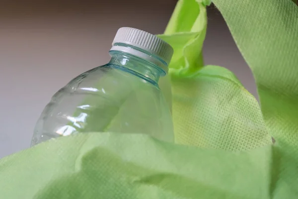 Plastikflasche mit Verschluss in der wiederverwendbaren grünen Einkaufstasche Nahaufnahme - Bild — Stockfoto