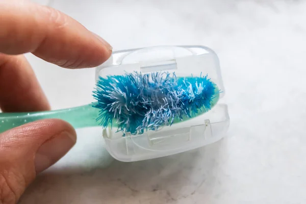 Woman hand opening the plastic sanitary cap with the old used toothbrush inside - Image — Stock Photo, Image