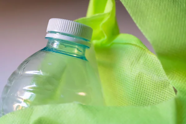 Plastová láhev s uzávěrem v zeleném nákupním vaku-obraz — Stock fotografie