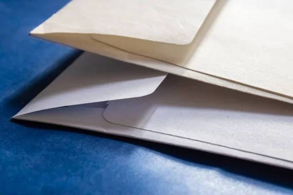 Mavi arka plan ile iki beyaz kağıt zarf closeup - Resim — Stok fotoğraf