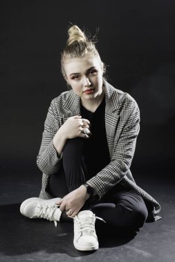 Stüdyo s karanlık bir arka plan üzerinde gri ceketli genç kız