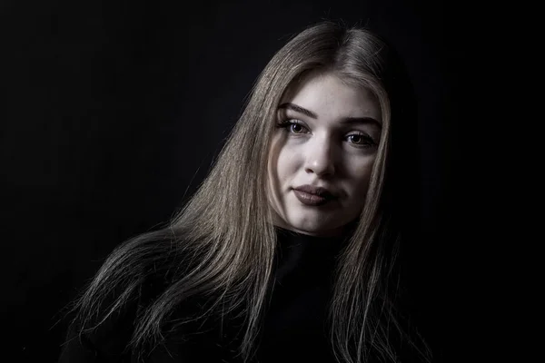 Retrato de una joven con un vestido negro sobre un fondo oscuro — Foto de Stock