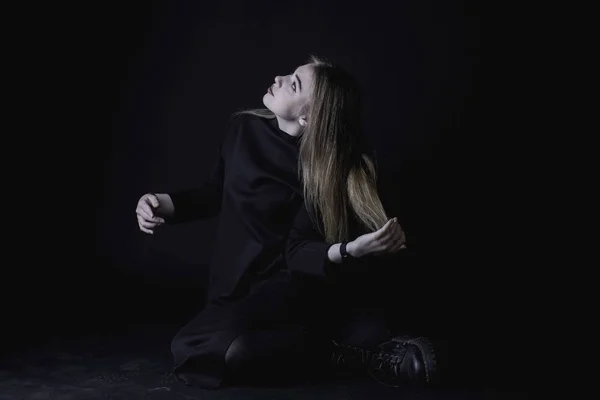 Νεαρό κορίτσι σε ένα μαύρο φόρεμα σε σκούρο φόντο στο στούντιο — Φωτογραφία Αρχείου