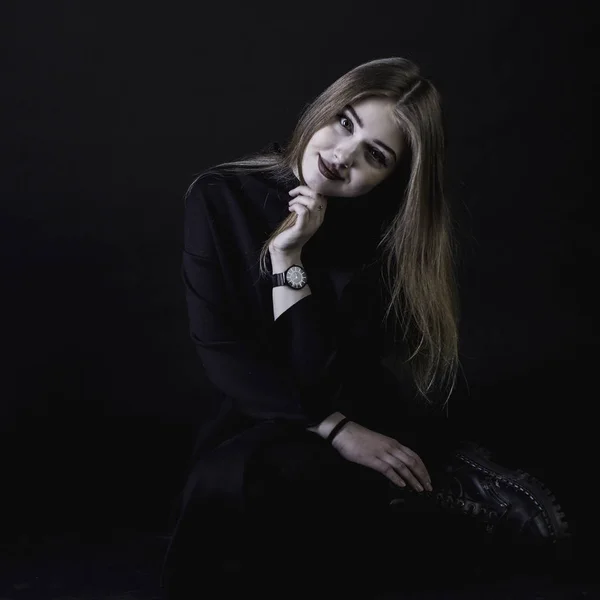 Jovem menina em um vestido preto em um fundo escuro no estúdio — Fotografia de Stock