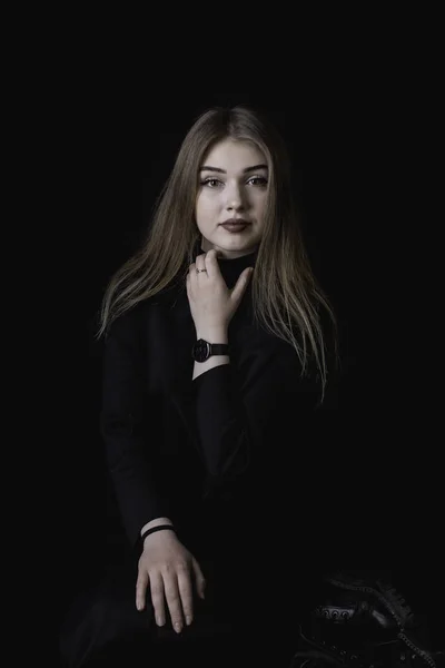 Fiatal lány, egy fekete ruhás, sötét háttér előtt a stúdióban — Stock Fotó