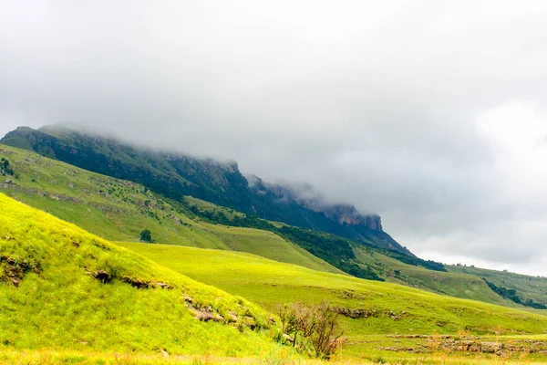 色南アフリカ共和国 Drakensberge 風光明媚な自然 緑の平面と岩と晴れた日に茂みの密な雲の山の風光明媚な風景写真をパノラマ — ストック写真