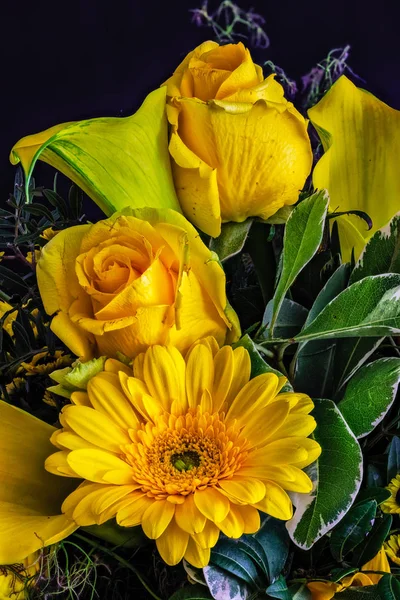 Vintage flower bouquet with open rose, gerbera and calla blossoms,fine art still life floral detailed texture macro of yellow blooms and green leaves on black background