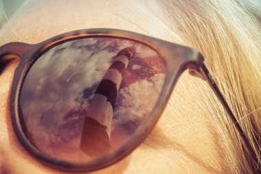 Genç güzel sarışın kadın tarafından suni güneş gözlüğü deniz feneri yansıması. Tatil kavramı