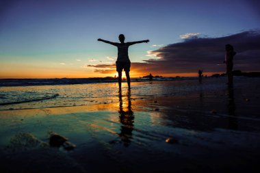 Özgürlük kavramı. kum sahilde günbatımı sırasında yürüyüş kollarını açarak siluet kız. Yansımalar