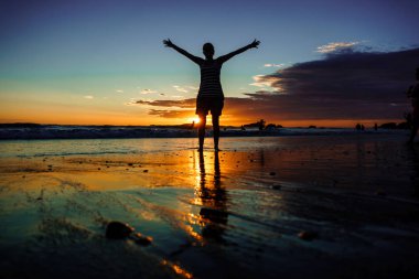 Özgürlük kavramı. kum sahilde günbatımı sırasında yürüyüş kollarını açarak siluet kız. Yansımalar